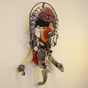 Guru made with hockey sticks, a big metal blade, automotive pistons, and the cylinder head of an engine.