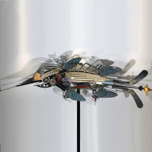 A crocodile constructed of golf clubs, hockey sticks, ceramic fins, a hedge trimmer and various other machine parts.