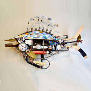 A tiger fish with golf clubs, a post hole digger mouth, hockey sticks, a boat propeller and formica chips with various machine parts. It can be freestanding.