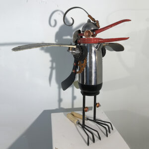 A pelican constructed of a coffee pot, hockey sticks and hand rakes.