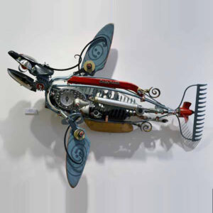 A fish made of ceramic fins, a boat propeller a rake, bicycle seat, and welded steel